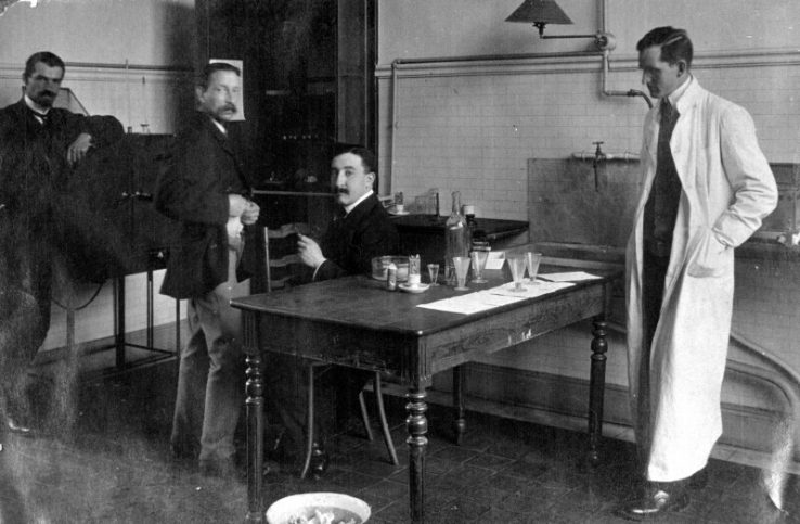 Black and white photo of Dr. John Fitzgerald in white lab coat with other researchers at table