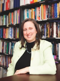 Profile of Esme Fuller-Thomson in foreground. Bookshelves in background.