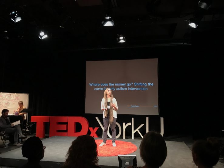 Wendy Ungar centre with red and white TedX York U signage and screen in background
