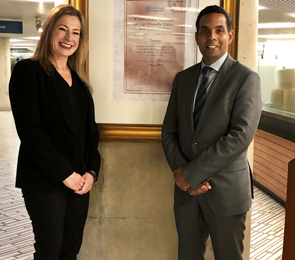 Photo of Andrea Austen Left and Dr. Samir Sinha right in front of pillar at Toronto City Hall