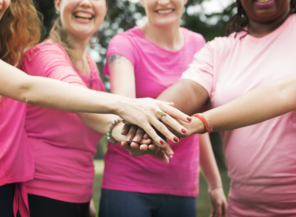 Women fighting breast cancer with hands in, in pink t-shirts