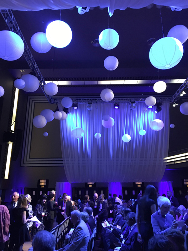 Arbor Award venue at The Carlu with blue back drop and lighting and decorative globes hanging from ceiling