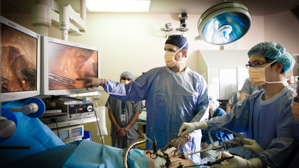 Surgical team conducting procedure on patient with video display and black box in operation