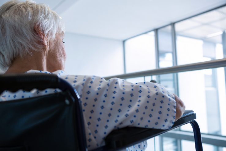 Close-up of senior patient on wheelchair in hospital passageway at hospital