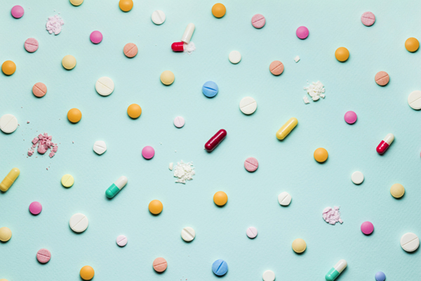 A photo of different medicinal drugs, tablets and pills on blue background.