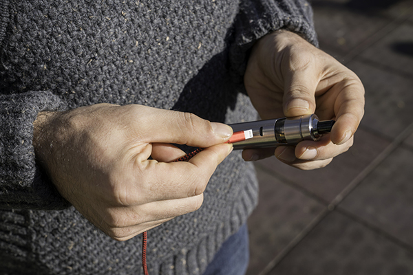 A man charging an electronic cigarette in the park