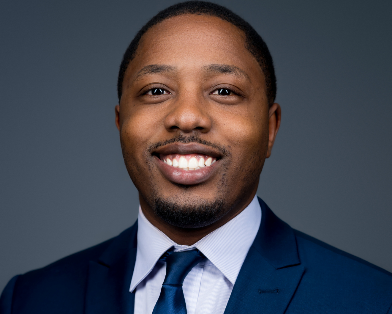 A person smiling in front of a blank background. Dr. Adom Bondzi-Simpson presented with the Award for Young Leaders from the Canadian Medical Association (CMA)