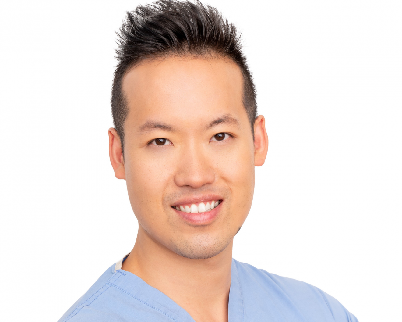 A medical professional dressed in scrubs smiling warmly in front of a white background. Grant to Support Breast Cancer Research