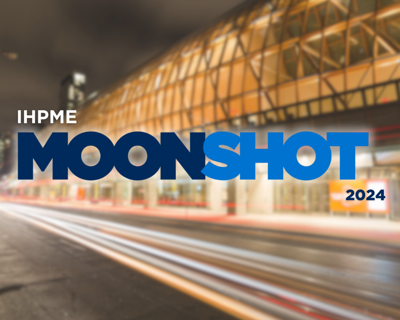 Banner for IHPME Moonshot 2024 event, featuring the bold text 'IHPME Moonshot' in a large, blue font. The word 'Moon' is in a darker shade of blue, while 'Shot' is in a lighter blue. The background shows a blurred city street with lights, adding a dynamic, fast-paced feel to the image.