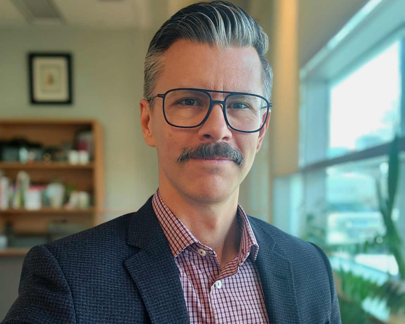 A professionally dressed man sitting in an office with a bookshelf visible in the background. MHSc student 
Jeff Reinhart.