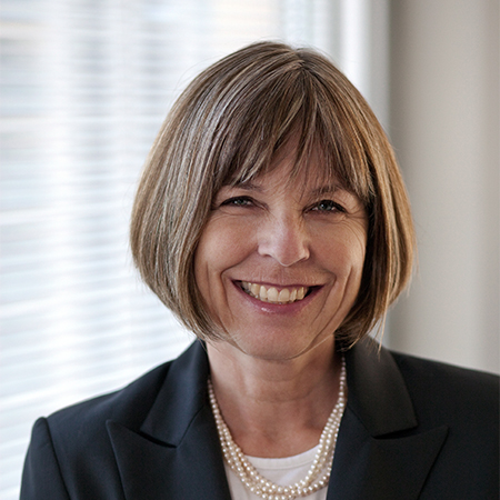 A professional woman smiling in front of a bright backdrop.